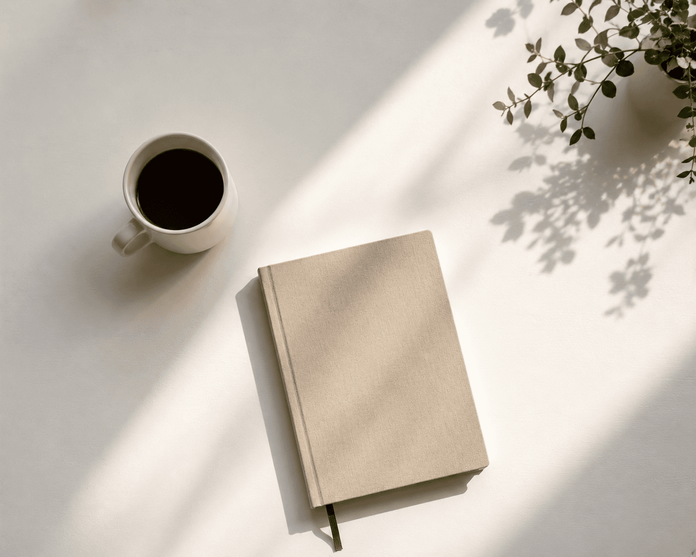 A journal and coffee on a clean white desk with morning light